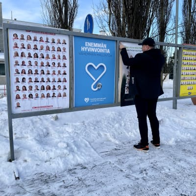 Mikko Jokipii laittamassa uutta Vihreiden vaalimainosta telineeseen.