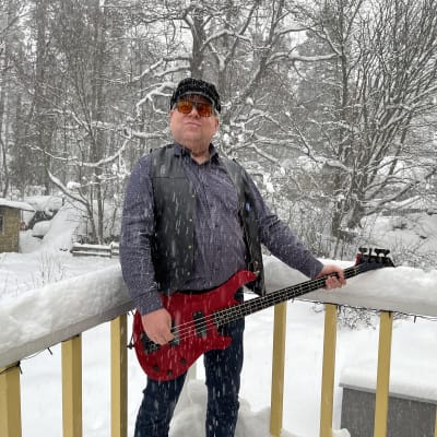 Mies seisoo lumisateessa basson kanssa