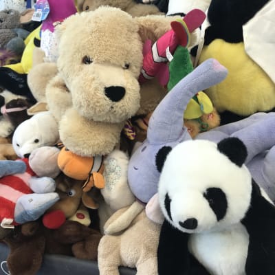 Iso kasa pehmoleluja, jossa päällimmäisenä vaaleanruskea koira, musta-valkoinen panda ja vaaleansininen elefantti. 