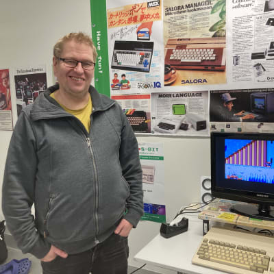 Mies seisoo vanhan tietokoneen vierellä.