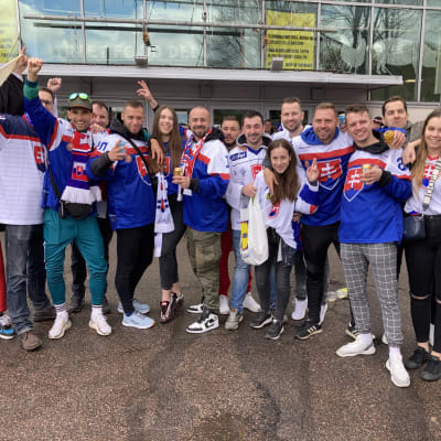 Slovakian jääkiekkojoukkueen paitoihin pukeutuneet fanit poseeraavat rivissä ja tuulettavat.