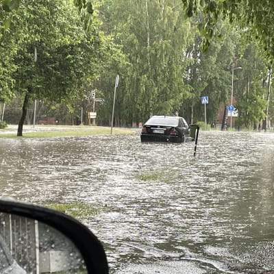 En bil på en översvämmad gata.