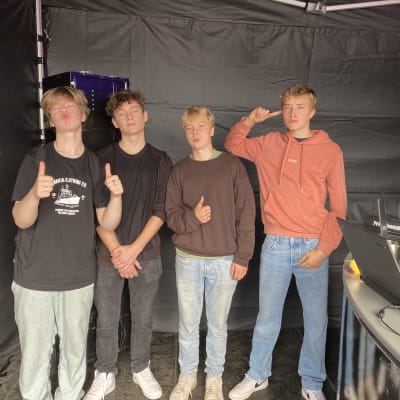 fyra unga killar, pojkar står inne i ett svart tält. Svenska Yles escape room på Ekenäs höstmarknad.