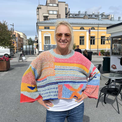Kvinna står med händerna på höften på ett torg