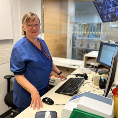 Kvinnlig vårdare i 60-årsåldern framför en dator.