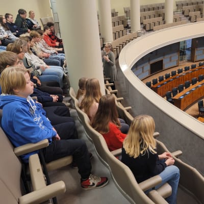 Kyrkbackens skolas elever sitter i plenisalen i riksdagen