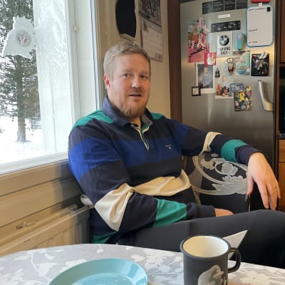 Mies istuu pöydän ääressä.