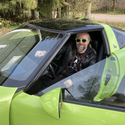 Mies aurinkolasit päällä vihreässä sporttiautossa.