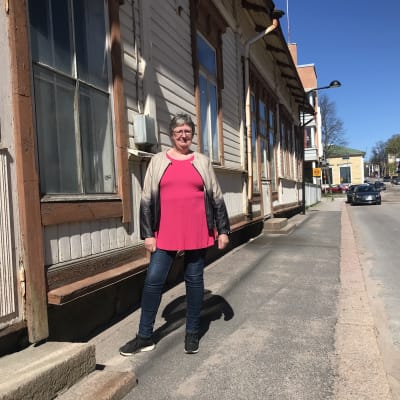 Thérèse Meriheinä står utanför ett gammalt beige hus i Lovisa medan solen skiner.