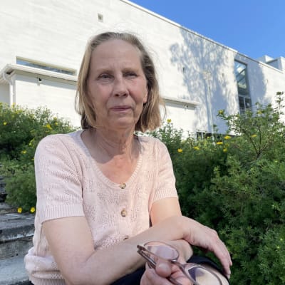 Kajaanin Runoviikon taiteellinen johtaja Kati Outinen istuu portailla puutarhassa.