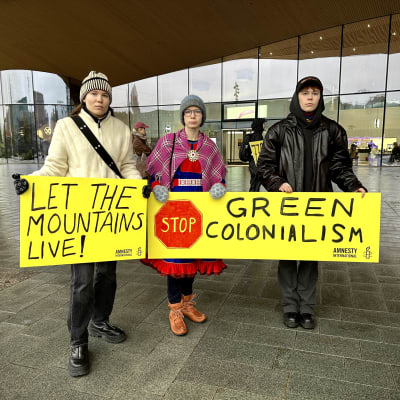 Saamelaisnuoret pitämässä keltaisia kylttejä, joissa lukee ”Let the mountains live” ja ”Stop green colonialism” Helsingissä Amnesty Sápmin järjestämässä tukimielenosoituksessa. 