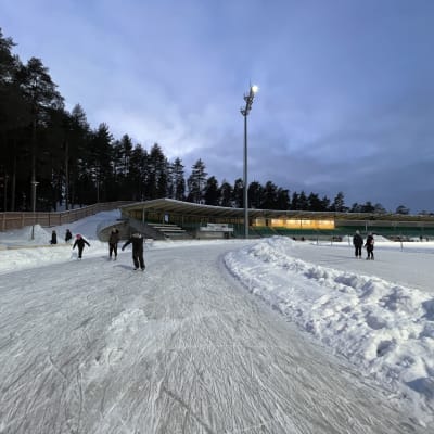 Ihmiset luistelevat Harjun jääradalla. 