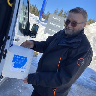 Ahti Pajunen Adblue-kanisterin kanssa autonsa vierellä huoltoasemalla.