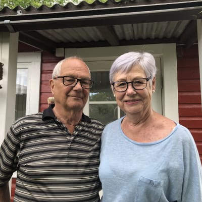 Pariskunta Tauno ja Hannele Telaranta punaisen siirtolapuutarhamökin edustalla.