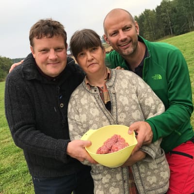 Michael Björklund, Ia Asén och Matias Jungar, fotograferade på en äng. De håller i en plastbunke med lammfärs.