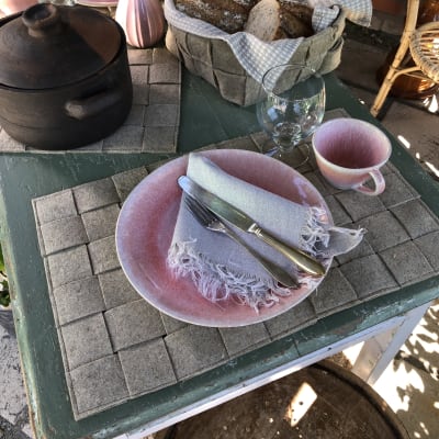 Ett bord är dukat med bordstabletter, grytunderlägg och brödkorg gjorda av linfilt