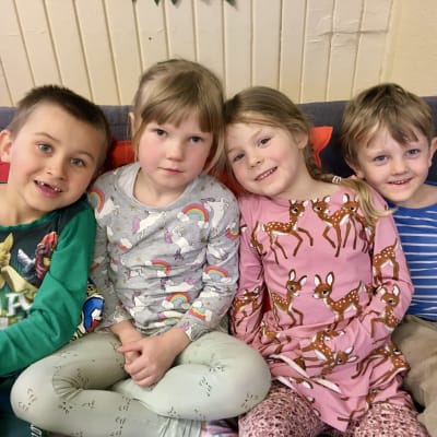 Fyra glada barn sitter tillsammans i en soffa.