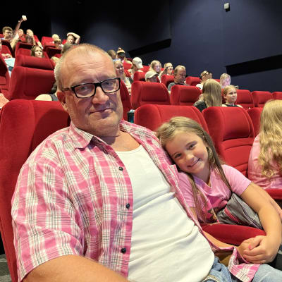 Mies ja pieni tyttö istumassa elokuvateatterin salissa.