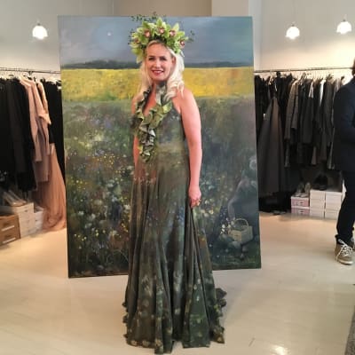 Konstnären Johanna Oras poserar i en grön klänning med blommor.