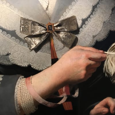 En målning av en dam klädd i spetsklänning och med en fjäder i handen.