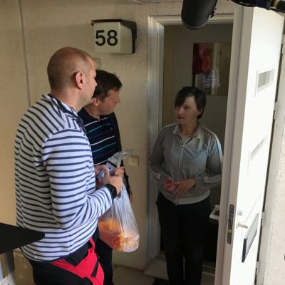 Matias Jungar och Michael Björklund tar emot kantareller i en plastpåse av Maria Holmberg.