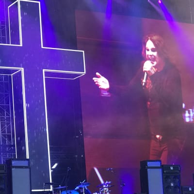 Ozzy Osbourne med stort kors på scen.
