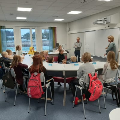 Skolbarn kring ett hästskoformat bord.