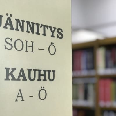 Kirjaston hyllyssä oleva kyltti, jännitus ja kauhu.