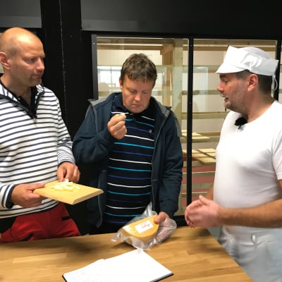 Per-Olof Friman visar upp en ost för Matias Jungar och Michael Björklund.