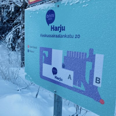 Onnikoti Harjun opastekyltti, johon on merkitty palvelukotiin kuuluvat rakennukset. Kyltti on kuurassa, ympärillä lumihanki.