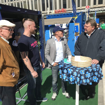Fyra män diskuterar utanför Sverigedemokraternas valstuga.