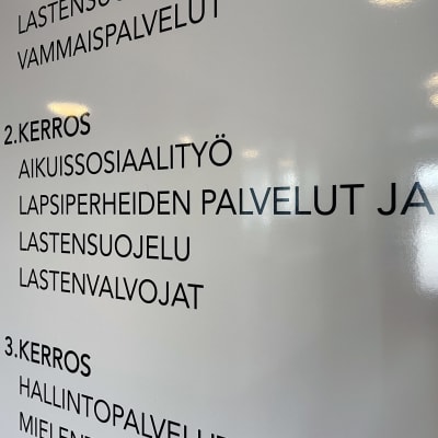 Opastekyltti lapsiperhepalveluiden ja lastensuojelun seinällä.