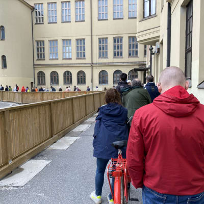 En kö med människor med ryggen mot kameran.