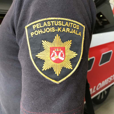 Pohjois-Karjalan pelastulaitoksen logo pelastuslaitoksen työntekijän t-paidan hihassa.