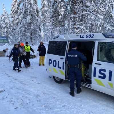 Poliisit taluttavat mielenosoittajaa poliisiautoon.