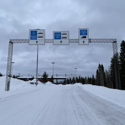 Rajavartioaseman kyltit tien yllä talvisella tiellä.