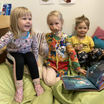 Iloisia lapsia satusohvalla satukirjojen kanssa.