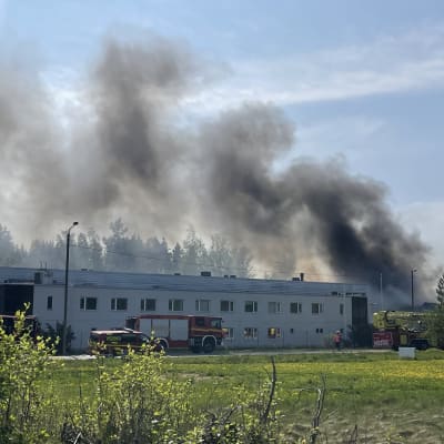 Paloautoja palavan rakennuksen edessä.