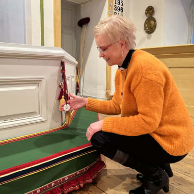 Kirkkoherra Päivi Aikasalo esittelee Utsjoen kirkon alttaria koristavia tupsuja ja Ilmari Tapiolan luutyötä.