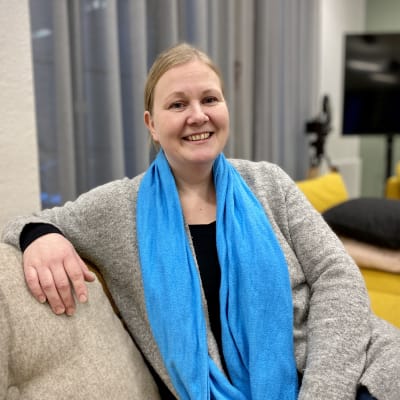 Ratsastusterapeutti Sari Jaatinen istuu sohvalla ja katsoo kameraan