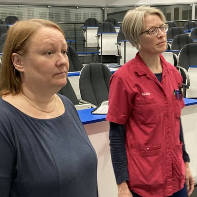 Satu Jyräköski seisoo työkaveri vierellään auditoriossa lauluharjoituksissa.