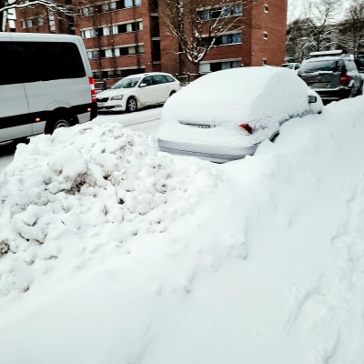 Lumikasaan hautautunut parkeerattu auto.