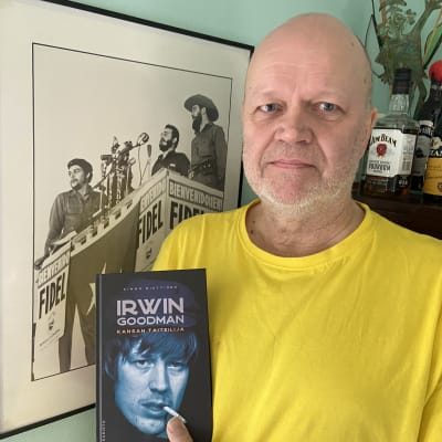 Irwin Goodman - Kansan taiteilija -kirjan kirjoittaja Kimmo Miettinen Irwin -tarinoita sisältävä kirja kädessään.