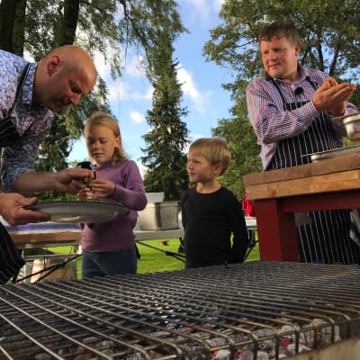 Emelie och Arvid Munsterhjelm står i ett provisoriskt utomhuskök med Matias Jungar och Michael Björklund.