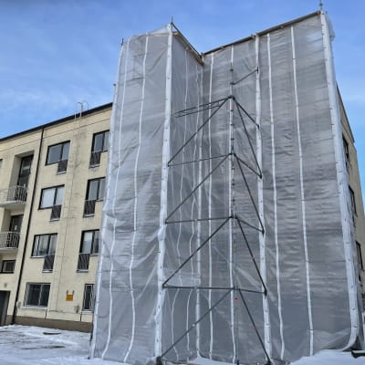 Kerrostalon julkisivun eteen on laitettu muovinen huppu. 