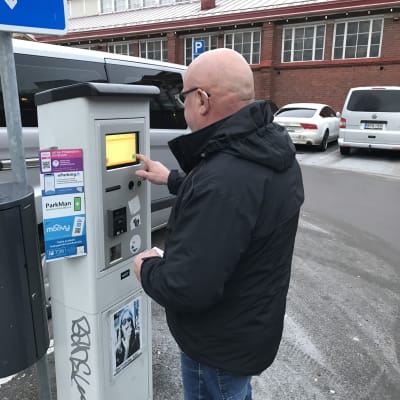 Tapani Kanto näppäilee Turun kauppahallin pysäköintialueella parkkiautomaatin painikkeita.