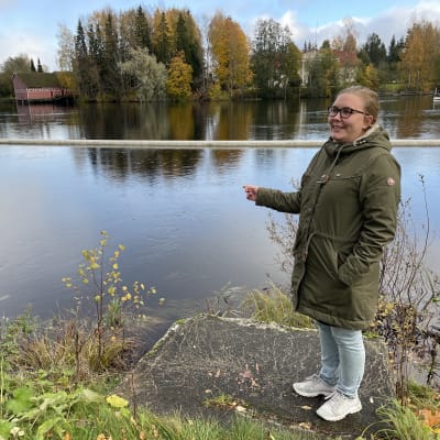 Nainen seisoo joen varrella.