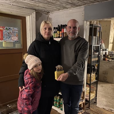 En ljushårig kvinna med sin dotter och en man som poserar på bild.