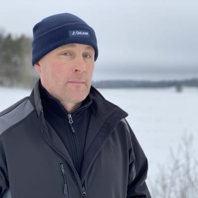 Lypsykarjatilan isäntä Jukka Velling katsoo kameraan. Taustalla on luminen maalaismaisema.