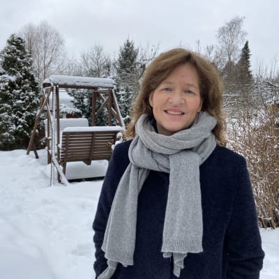 En kvinna i en snöig trädgård. 